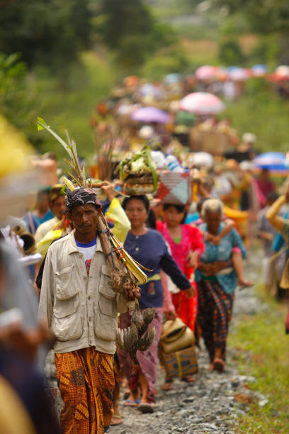A portrait of a Balinese man carrying the offerings with crowded people on the background heading to the cremation ceremony location. stock photo