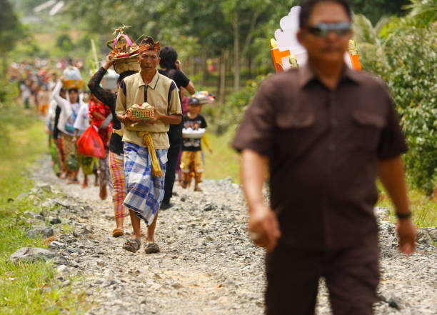 A portrait of a Balinese man carrying the offerings with crowded people on the background heading to the cremation ceremony location. stock photo
