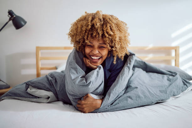 Portrait of a Beautiful Woman in Bed Snuggled Under the Covers stock photo