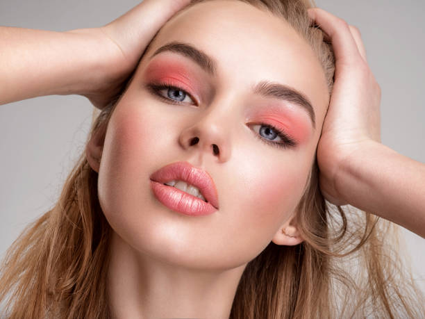 Portrait of a beautiful woman with a coral color makeup. Attractive blond  girl with  bright fashion make-up, posing at studio. Beautiful female face. Closeup portrait of pretty lady. Fashion model. stock photo