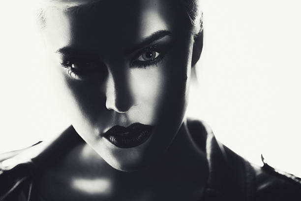 Portrait of a beautiful woman with a strong dark makeup. Black and white portrait of a beautiful blonde woman with a black smokey eyes make-up and black lips, wearing black ramones leather jacket. chiaroscuro stock pictures, royalty-free photos & images