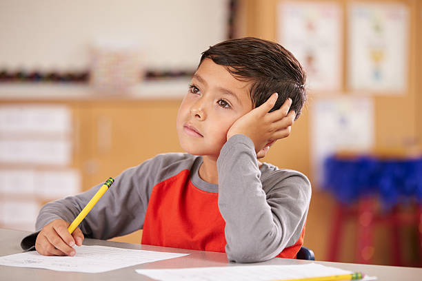 Portrait of a boy daydreaming in an elementary school class Portrait of a boy daydreaming in an elementary school class distracted stock pictures, royalty-free photos & images