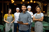 istock Portrait of a business owner smiling with his staff at a restaurant 1368500097