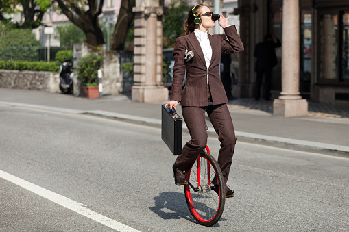 Portrait of a businessman on a unicycle drinking coffee