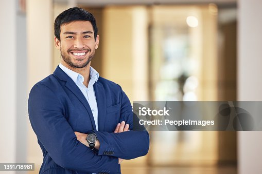 istock Portrait of a confident young businessman standing with his arms crossed in an office 1391718981