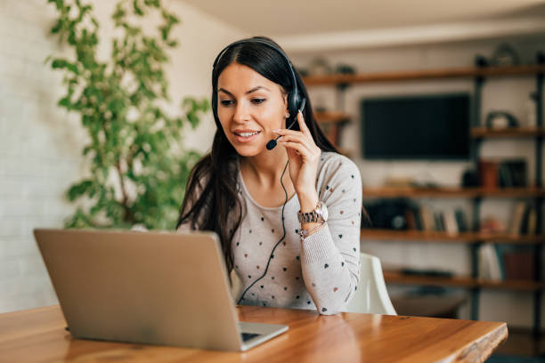 Portrait of a cute woman with headset and laptop at home office. Portrait of a cute woman with headset and laptop at home office. working at home stock pictures, royalty-free photos & images