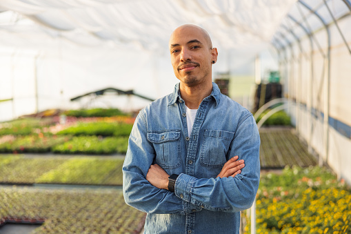 Mixed race male gardener standing with arms crossed and looking at the camera.