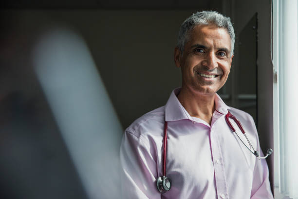 Portrait of a Doctor Portrait of a mature Asian doctor smiling at the camera. general practitioner stock pictures, royalty-free photos & images