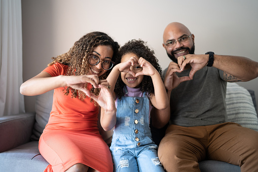 Portrait of a family doing heart-shape with hands at home