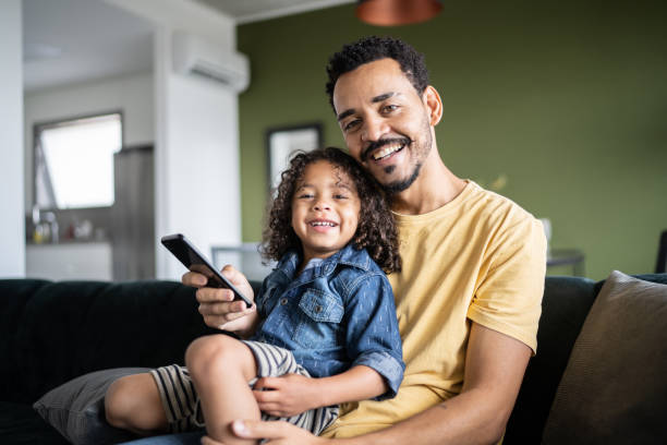 Portrait of a father and son holding a smartphone at home stock photo