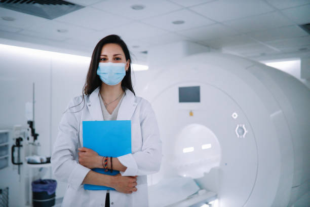 Portrait of a female doctor in the CT scanner room Portrait of a female doctor in the CT scanner room wearing a protective face mask. mri scan photos stock pictures, royalty-free photos & images