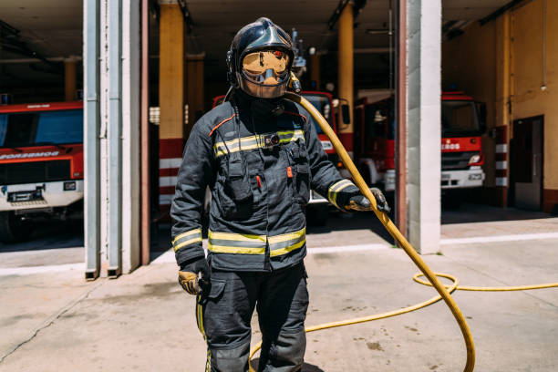 Portrait of a firefighter in uniform holding the fire hose with his shoulder stock photo