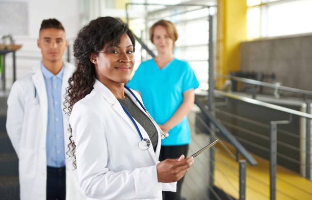 Portrait of a friendly female african american doctor and team in bright modern office stock photo