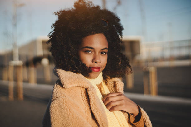 Portrait of a girl outdoors, winter An outdoor portrait of a young beautiful Brazilian girl in a warm casual outfit and with curly afro hair standing on evening street and looking at the camera, winder sunset in Lisbon, Portugal hot latino girl stock pictures, royalty-free photos & images
