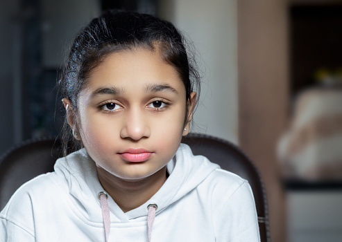 Portrait of an Indian teenage girl looking at the camera and contemplating deeply with a blank expression.