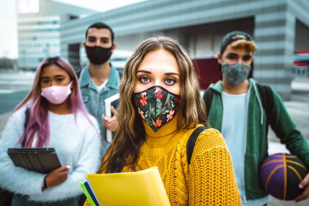 Portrait of a group of multiracial people covered by face masks - New normal lifestyle concept with students going to school - Vintage filter stock photo