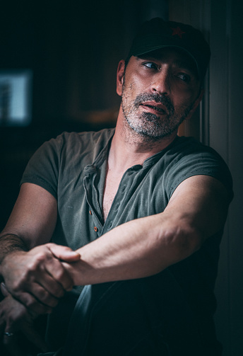Close up of a handsome mature man wearing gray t-shirt  leaning against the door