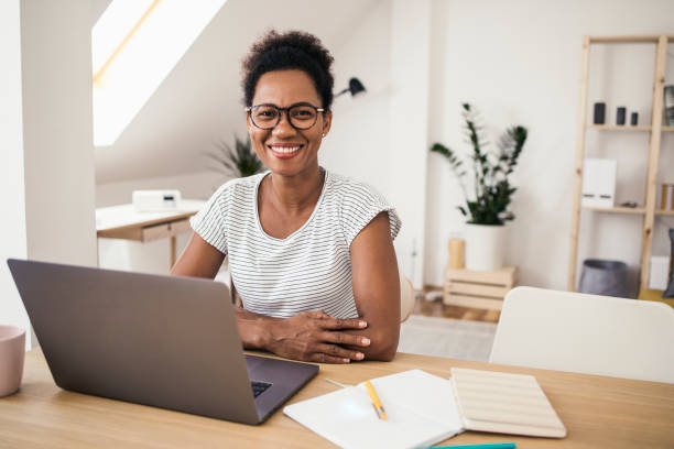 Portrait of a happy Afro woman working on her laptop stock photo