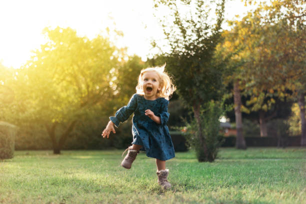 Portrait of a happy little girl running by smiling in a public park stock photo