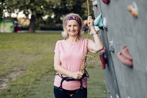 Portrait of a happy senior woman trying sport climbing stock photo