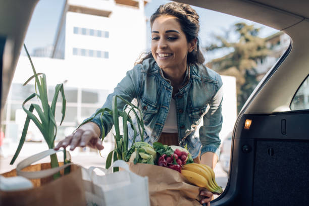 Portrait of a happy woman packing groceries into the car trunk stock photo