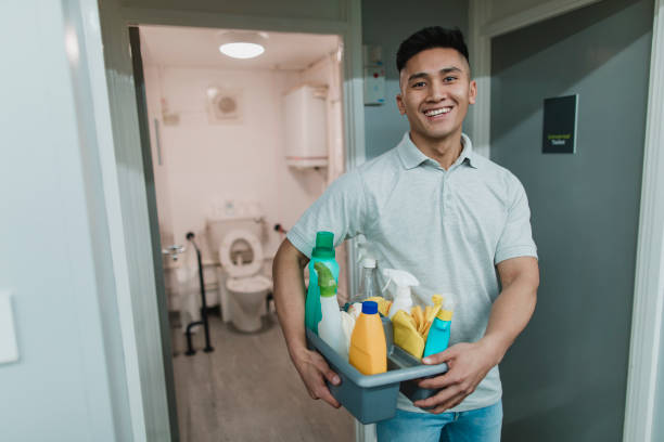 Portrait of a Male Cleaner Portrait of a young, male cleaner at work. He is holding a tray of cleaning products. cleaner stock pictures, royalty-free photos & images