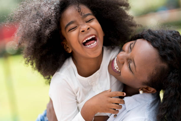 Portrait of a mother and daughter having fun outdoors Portrait of an African American mother and daughter having fun outdoors and laughing - lifestyle concepts tickling beautiful women pictures stock pictures, royalty-free photos & images