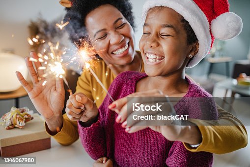 istock Portrait of a mother and daughter holding New Year's sparklers at home 1346067980