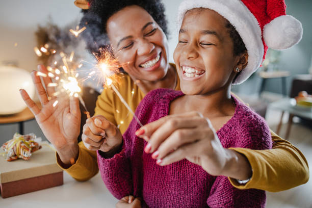 Portrait of a mother and daughter holding New Year's sparklers at home stock photo