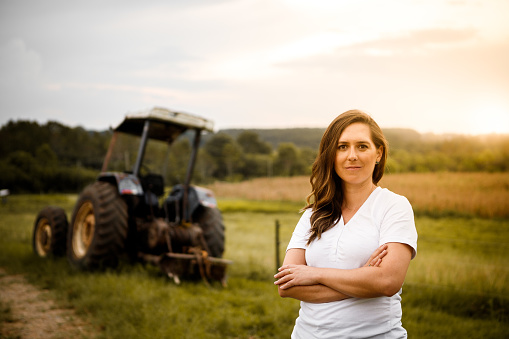 portrait of a professional woman in the field of agronomy in front of a tractor
