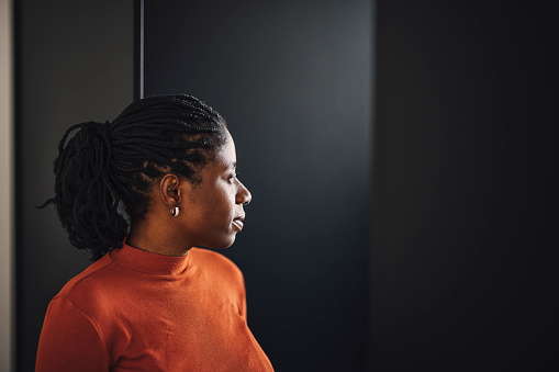 Businesswoman in orange shirt standing over a black background and looking away