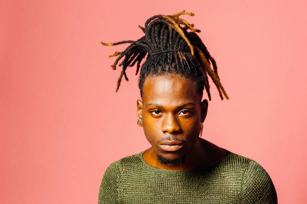 Portrait of a serious  young man in with cool dreadlocks hairstyle looking at camera, isolated on pink stock photo