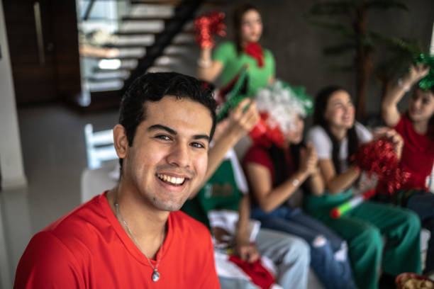 portrait of a teenage latin boy watching the mexico soccer team playing at home with friends - soccer mexico 個照片及圖片檔