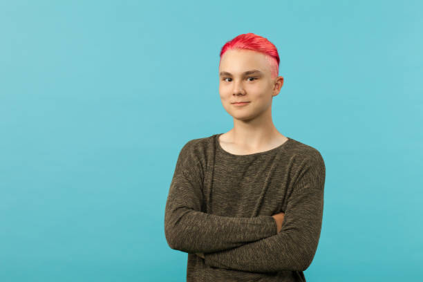 portrait of a teenager boy with pink hair in the studio on a blue background portrait of a teenager boy with pink hair in the studio on a blue background pink hair stock pictures, royalty-free photos & images