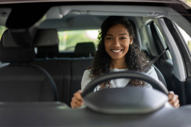 portrait of a woman looking very happy driving a car - driving imagens e fotografias de stock