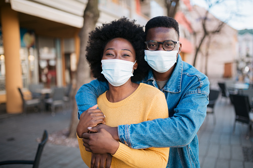 Portrait of an African American couple, happy and smiling behind the protective face masks that they are wearing