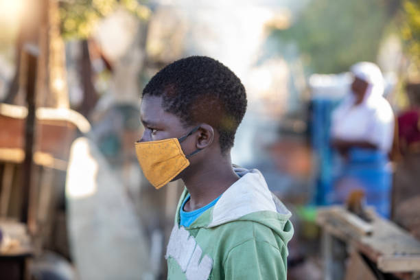 portrait of a young African man portrait of a young African man, with a yellow mask, walking in the yard, mom in the background botswana stock pictures, royalty-free photos & images