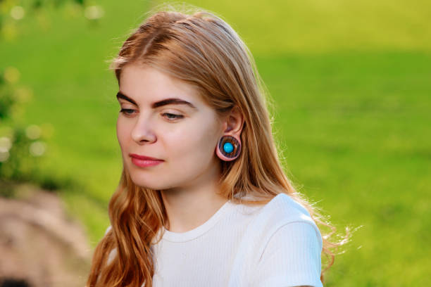 Portrait of a young beautiful woman with wooden tunnels in her ears stock photo