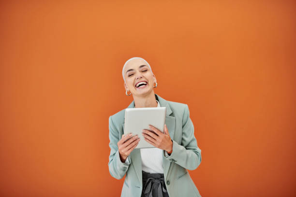 Portrait of a young businesswoman using a digital against an orange background stock photo