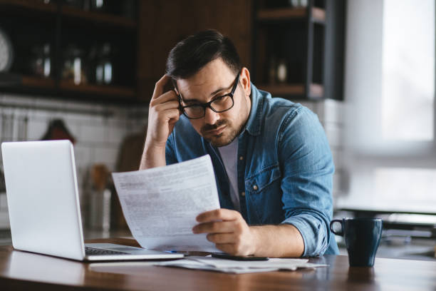 Portrait of a young man checking home finances Portrait of a young man checking home finances bank account stock pictures, royalty-free photos & images