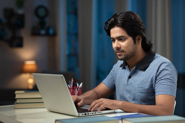 portrait of a young men university student using laptop and studying at home:- stock photo stock photo