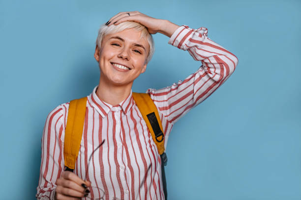 Portrait of a young woman against blue background Portrait of a short haired young woman with a bag against blue background. white hair young woman stock pictures, royalty-free photos & images