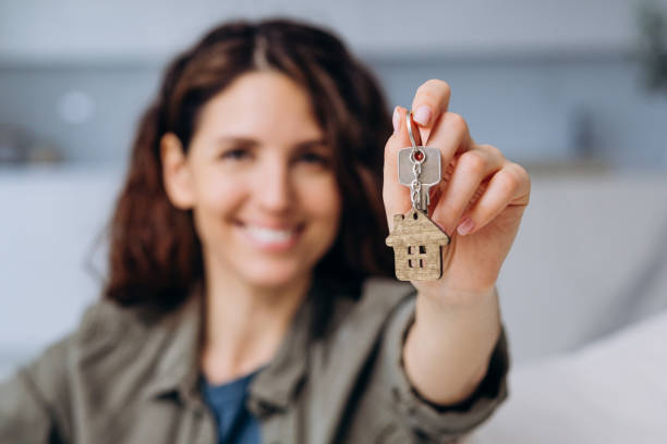 Portrait of a young woman shows the keys to a new apartment with a house, close-up stock photo