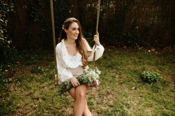 Portrait of a young woman sitting on a swing stock photo