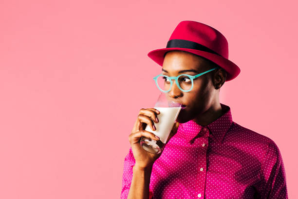 Portrait of a young woman with hat and glasses drinking milk stock photo