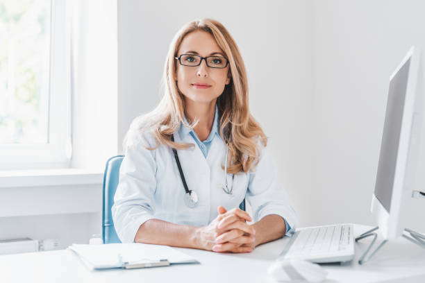 Portrait of adult female doctor sitting at desk in office clinic Portrait of adult female doctor sitting at desk in office clinic female doctor stock pictures, royalty-free photos & images