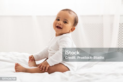 istock Portrait Of African Baby Toddler Smiling Sitting On Bed Indoor 1311426758