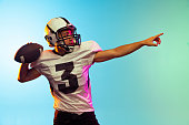 istock Portrait of American football player training isolated on blue studio background in neon light. Concept of sport, competition 1332130634