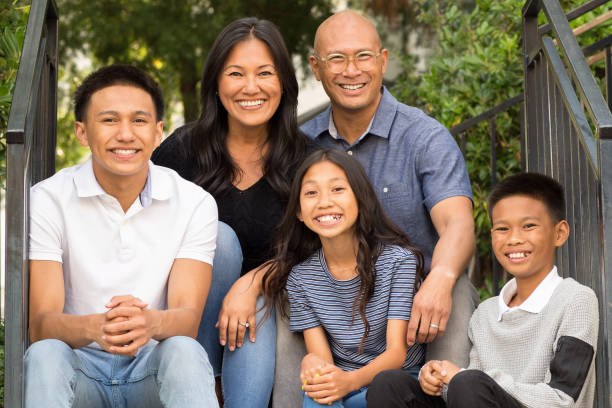 Portrait of an Asian family laughing and talking outside. Happy family sitting outside talking and spending time together. filipino family stock pictures, royalty-free photos & images