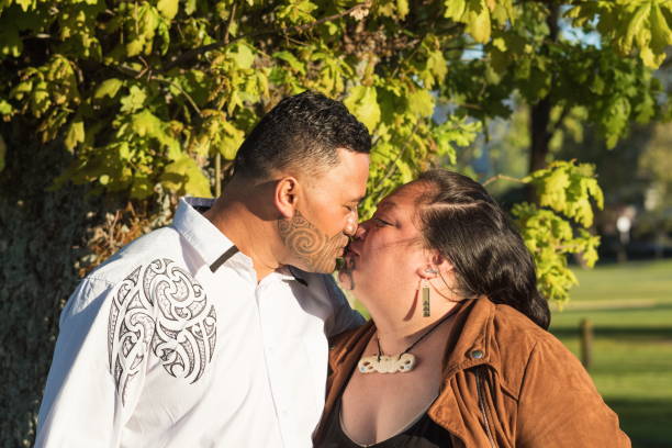 Portrait of an attractive Maori couple kissing taken outdoors stock photo